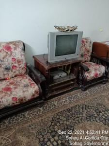 a living room with two chairs and a tv at سوهاج الجديدة 