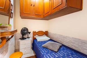 Dormitorio pequeño con cama y armarios de madera en Quarto em casa de vila em Botafogo, Rio de Janeiro en Río de Janeiro