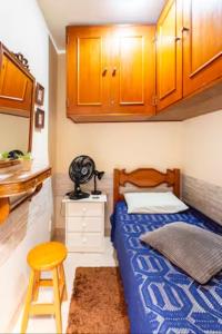 1 dormitorio con cama, taburete y armarios en Quarto em casa de vila em Botafogo, Rio de Janeiro, en Río de Janeiro