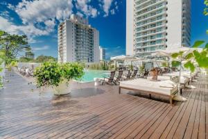 eine Holzterrasse mit Stühlen, einem Pool und Gebäuden in der Unterkunft Divino apartamento en edificio de lujo en Punta del este in Punta del Este