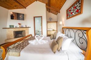 a bedroom with a large white bed with a fireplace at Pousada Nascer da Lua in Monte Verde