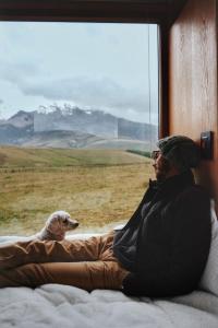 a man and a dog looking out of a window at Nomads Ecuador in Chimborazo