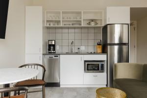 La cuisine est équipée de placards blancs et d'un réfrigérateur en acier inoxydable. dans l'établissement Sonder The Artesian, à Denver