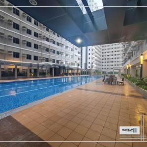 a large building with a swimming pool in front of it at Homely - SMDC Green 2 Residences, Dasmarinas City in Pasong Bayog