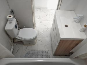 Baño blanco con aseo y lavamanos en Shugyla 1 Room, en Kooperator