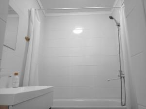 baño blanco con ducha y lavamanos en Shugyla 1 Room, en Kooperator