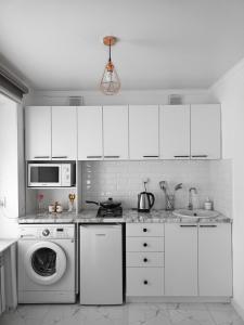 una cucina con armadietti bianchi e lavatrice di Shugyla 1 Room a Kooperator
