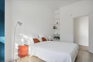 a white bedroom with a large white bed and a lamp at Cosy and renovated studio in heart of Paris XVieme in Paris