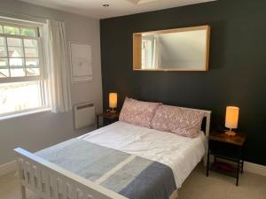 a bedroom with a bed with a mirror and two lamps at Modern loft retreat in the heart of Nailsworth in Nailsworth