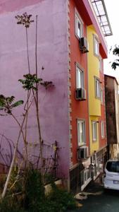 kolorowy budynek z samochodem zaparkowanym obok niego w obiekcie goldwinn turizm w mieście Trabzon