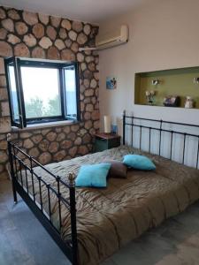 Un dormitorio con una cama con almohadas azules y una ventana en Korina's house, en Loutsa