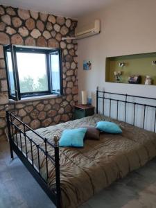 a bedroom with a bed with blue pillows and a window at Korina's house in Loutsa