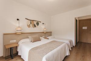2 camas en una habitación con paredes blancas en Hotel Catalunya Park, en Ribes de Freser