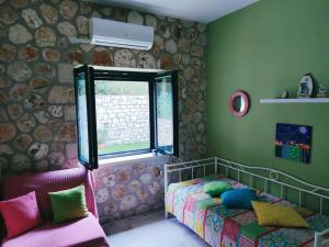 Un dormitorio con una cama con almohadas de colores y una ventana en Korina's house, en Loutsa