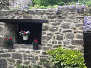 uma parede de pedra com dois vasos de flores numa janela em Maison Médiévale em Dinan
