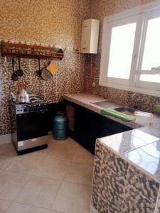 a kitchen with a stove and a sink and a window at Villa Mama Swiriya Atlantique in Souira Guedima