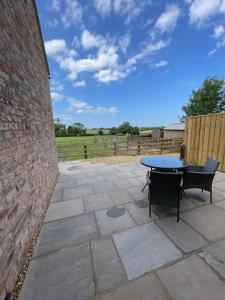 een patio met een tafel en stoelen en een bakstenen muur bij Converted Bullamoor Barns, Northallerton in Northallerton