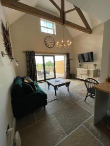 een woonkamer met een tafel en een klok aan de muur bij Converted Bullamoor Barns, Northallerton in Northallerton