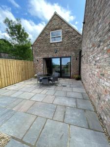 a patio with a table and a brick building at Converted Bullamoor Barns, Northallerton in Northallerton