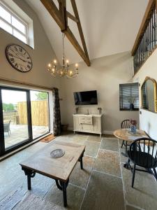 een woonkamer met een tafel en een klok aan de muur bij Converted Bullamoor Barns, Northallerton in Northallerton