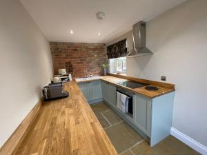 a kitchen with blue cabinets and a brick wall at Converted Bullamoor Barns, Northallerton in Northallerton