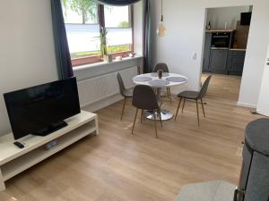 Una sala de estar con televisión, mesa y sillas. en FeldQuartier, en Grebenstein