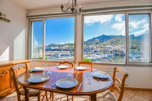 a dining room with a table and chairs and windows at Le Cabanon des Goudes - Vue mer et parking in Marseille
