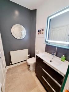 a bathroom with a sink and a toilet and a mirror at Cosy Family Haven: Spacious 3-Bedroom Retreat in Christchurch in Iford