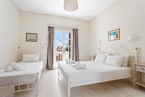 a white bedroom with two beds and a balcony at Villa Kalomira in Spetses