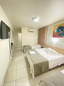 a hotel room with two beds and a painting on the wall at Hotel Marajó in Uberlândia