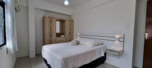1 dormitorio con 1 cama con manta blanca en Residencial Las Rocas II, en Florianópolis