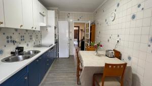 uma cozinha com armários azuis, um lavatório e uma mesa em Apartamento céntrico en Azpeitia em Azpeitia