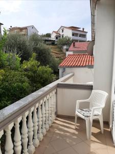 una silla blanca sentada en el balcón de una casa en Anka Bunić, en Rab