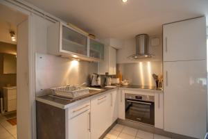 une petite cuisine avec des armoires blanches et un évier dans l'établissement Essey-St Bohème 6 pers parking apt en souplex, à Essey-lès-Nancy