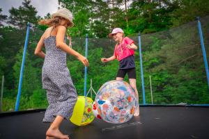 a boy and a girl playing on a trampoline at Osada Wilaneska domki Mikołajki Mazury in Mikołajki