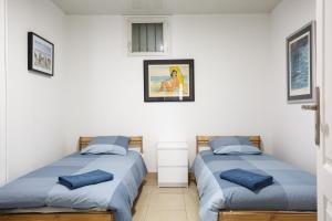 2 camas en una habitación con paredes blancas y almohadas azules en F2 Osakue en Aubervilliers