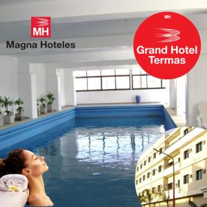 a woman laying in a swimming pool with the grand hotel tennnes logo at Grand Hotel by MH in Termas de Río Hondo