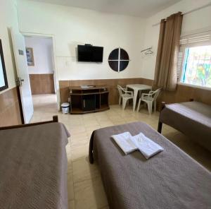 a hotel room with two beds and a television at Pousada El Shaddai in Campos dos Goytacazes