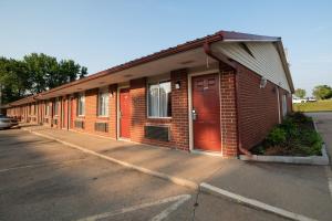 a brick building with a red door on a street at Americas Best Value Inn and Suites Siloam Springs in Siloam Springs