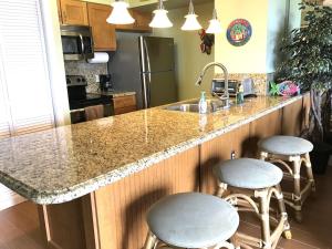 a kitchen with a granite counter top and stools at Tropical Daze Oceanfront Paradise in Tavernier