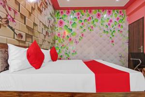 een slaapkamer met een wit bed met rode kussens bij OYO Flagship Govind Residency in Greater Noida