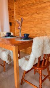 una mesa de madera con 2 sillas y 2 tazones. en Cabanas Kuntze, en Urubici