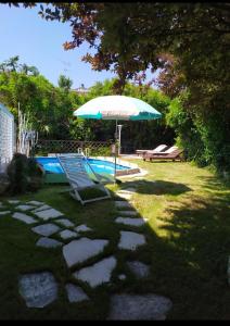 parasol i krzesła na patio przy basenie w obiekcie Villa Luna Lombarda w mieście Salò