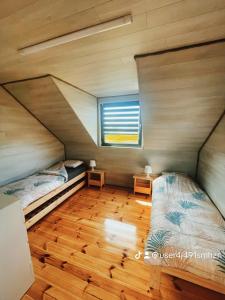 2 łóżka w małym pokoju z oknem w obiekcie K&J Domki Letniskowe w mieście Będzino