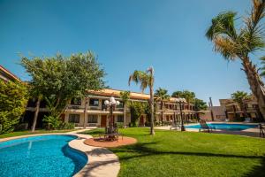 a resort with a swimming pool and palm trees at Hotel Colonial Ciudad Juarez in Ciudad Ju&aacute;rez