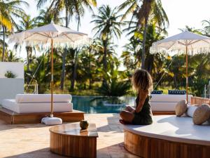 a woman sitting on a couch in front of a pool at MKNI Hotel - Ikaika Makani Experience in Prea