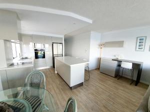 a kitchen with white cabinets and a table and chairs at Pandanus Shores Kings Beach in Caloundra
