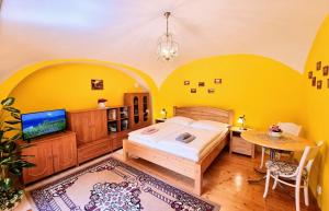 - une chambre avec des murs jaunes, un lit et une table dans l'établissement Historical house in the center Levoča with parking, à Levoča