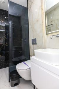 y baño con aseo, lavabo y ducha. en N HOTEL CITY CENTER BY NOSHI en Tirana