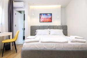 1 dormitorio con 1 cama grande y 1 silla amarilla en N HOTEL CITY CENTER BY NOSHI en Tirana